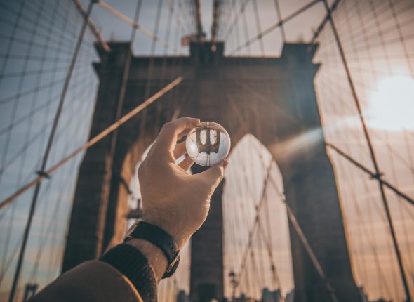 man holding ball facing Brooklyn Bridge, New York