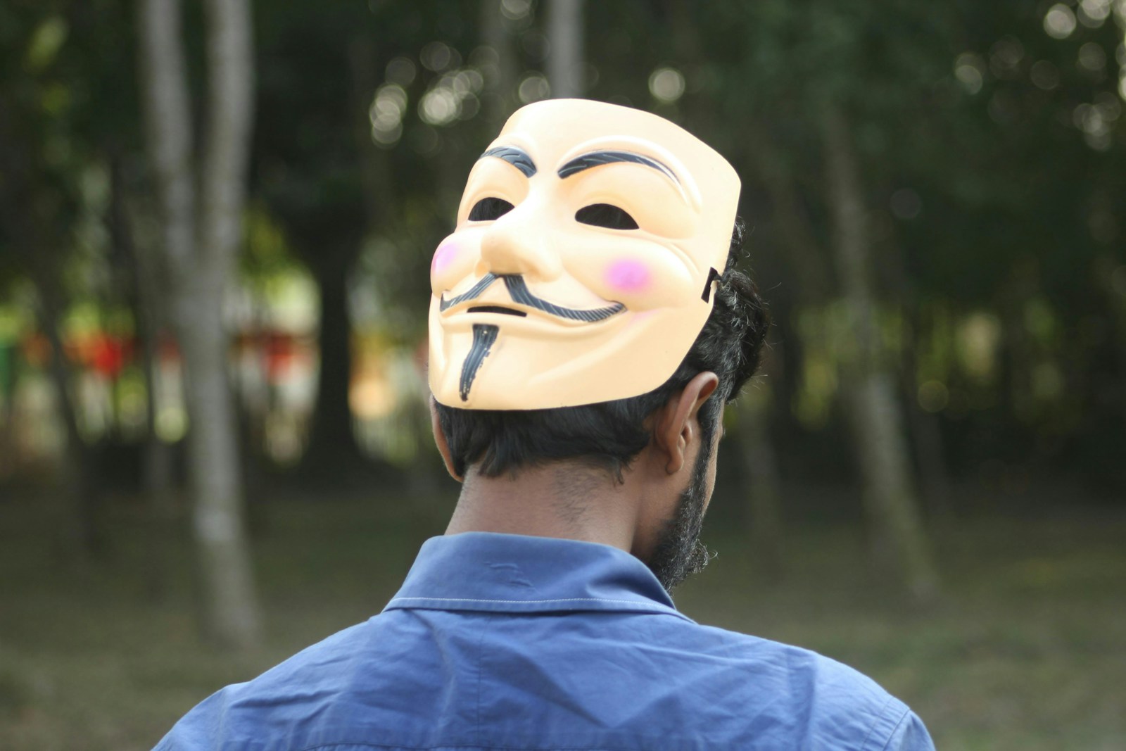 Man wearing an anonymous mask looking away.