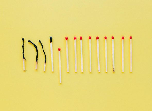 Artistic flat lay of burnt and unlit matches on a yellow surface, symbolizing burnout.